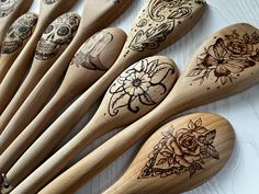 several wooden spoons with designs on them are lined up next to eachother