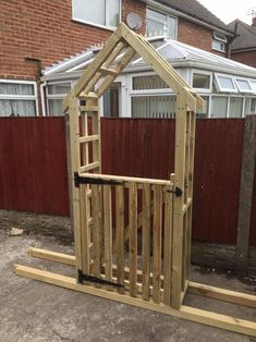 a small wooden structure sitting in the middle of a yard next to a fence and brick building