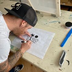 a man sitting at a table working on a piece of paper with a cat drawn on it