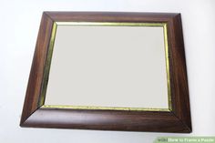 a mirror hanging on the wall with a wooden frame and gold trim around it's edge