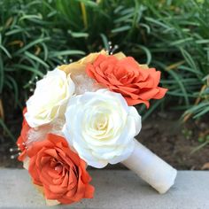 an orange and white bridal bouquet sitting on the ground