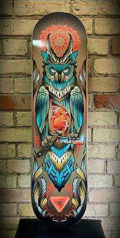 a skateboard with an owl design on the front and back side, against a brick wall