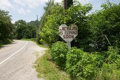 a sign that says jesus is coming soon on the side of the road next to some bushes