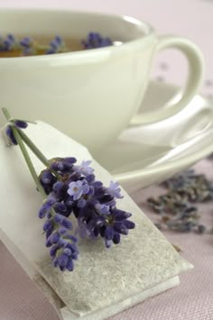 some lavender flowers are sitting on a napkin next to a cup and saucer,