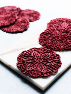 three red coasters sitting on top of a white plate next to a glass of milk