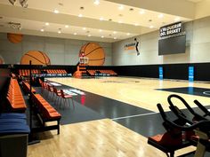 an indoor basketball court with orange seats and chairs on the sidelines in front of it