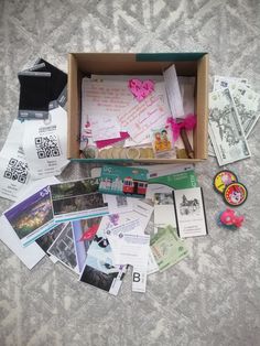 an open box filled with lots of papers and other items sitting on top of a bed