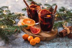 two glasses of mulled with blood oranges and cinnamon sticks on a wooden board