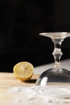 an empty wine glass sitting on top of a table next to a slice of lemon