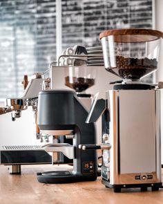 an espresso machine sitting on top of a wooden table next to a coffee maker