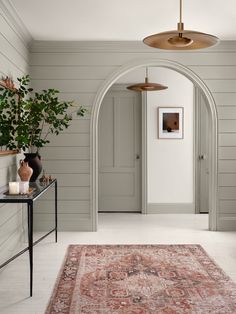 a hallway with an archway leading to another room and a rug on the floor in front of it