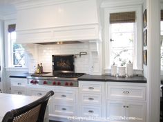 a kitchen with white cabinets and black counter tops is seen in this image from the dining room