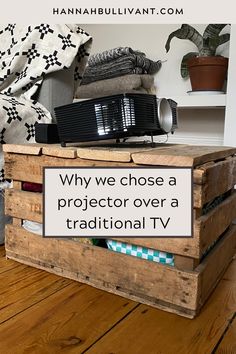 a wooden crate with a sign that says why we chose a projector over a traditional tv