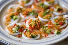 a white plate topped with deviled eggs covered in sauce