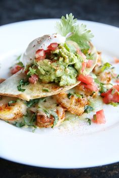 a white plate topped with tacos and guacamole on top of it