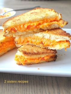 three grilled cheese sandwiches stacked on top of each other in front of a plate