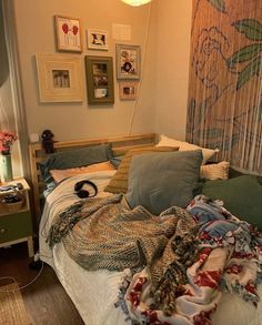 an unmade bed in a bedroom with pictures on the wall above it and blankets