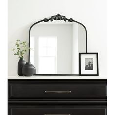 a black dresser with a mirror and vase on top