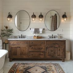 a bathroom with two sinks, mirrors and a rug in front of the bathtub