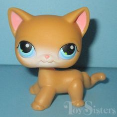 a close up of a small toy cat on a blue surface with the eyes wide open