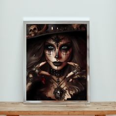 a framed photograph of a woman with makeup and skeleton hands in front of her face