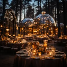 the tables are set with candles and place settings in front of glass domes at night