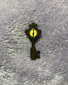 a yellow light on top of a black metal key with a chain attached to it