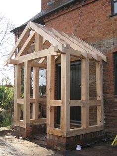 a house being built in front of a brick building with wood framing on the side