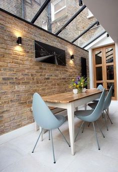 a dining room table with blue chairs under a skylight