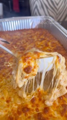 a spatula scooping cheese from a casserole dish in a metal pan