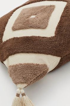 a brown and white pillow with tassels on it