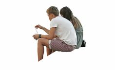 a man and woman sitting next to each other on top of a white wall with a kite flying in the air