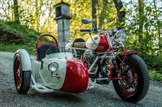 a red and white motorcycle with a side car on the road in front of some trees