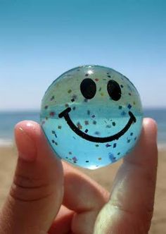 a hand holding a glass ball with a smiley face painted on it