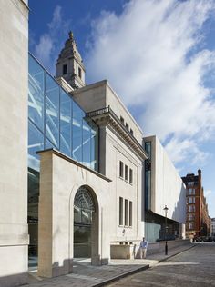 a building with a clock tower on the top of it's roof and people walking by