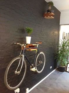 a bike mounted to the side of a brick wall next to a potted plant