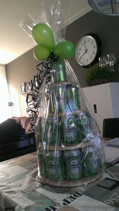 a table topped with lots of green beer bottles next to a wall clock and balloons