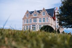 an old building with grass in front of it and a flag on the top floor