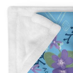 a blue blanket with purple flowers on it and a white fleece covering the edges