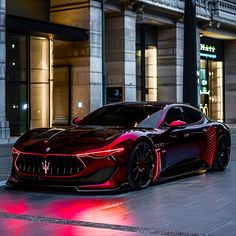 a red sports car parked in front of a building at night with its lights on