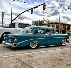 an old car is parked on the side of the road next to a white truck