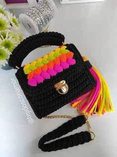 a crocheted handbag with multicolored tassels on the handle