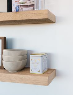 two wooden shelves with bowls on them and a box of tea next to the shelf