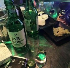 there are two bottles of alcohol on the table next to some plates with food and utensils