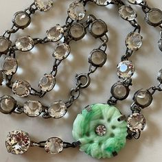 a necklace with a green flower on it and lots of crystal beads hanging from the chain