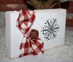 a wooden box with a red and white checkered scarf around it's neck