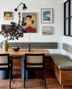 a dining room table with two chairs and a bench in front of the wall, along with pictures on the walls