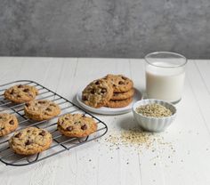 chocolate chip cookies cooling on a rack next to a glass of milk and bowl of oats