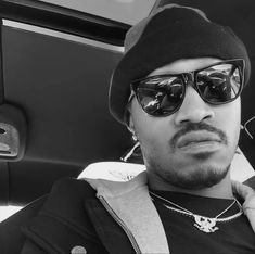 a man wearing sunglasses and a beanie sitting in a car