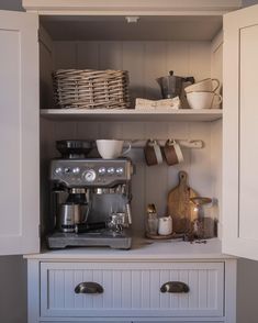 a coffee maker is sitting on top of the cupboards in this kitchen, and it's full of dishes